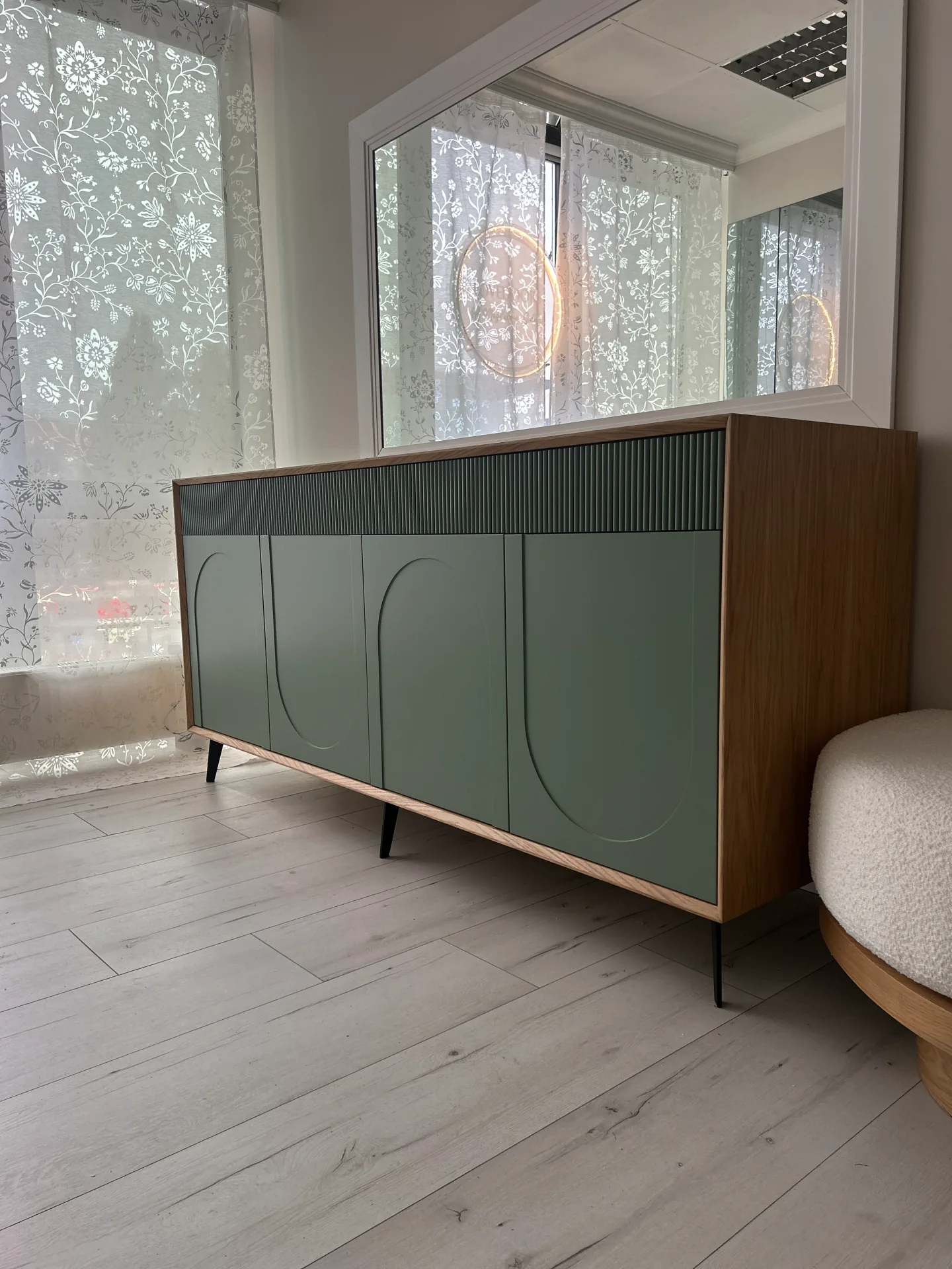 Niska szafka sideboard na wymiar ujęta w perspektywie, z szałwiowymi frontami z łukami i lamelami oraz litym dębowym blatem, na czarnych metalowych nóżkach w jasnym pokoju.