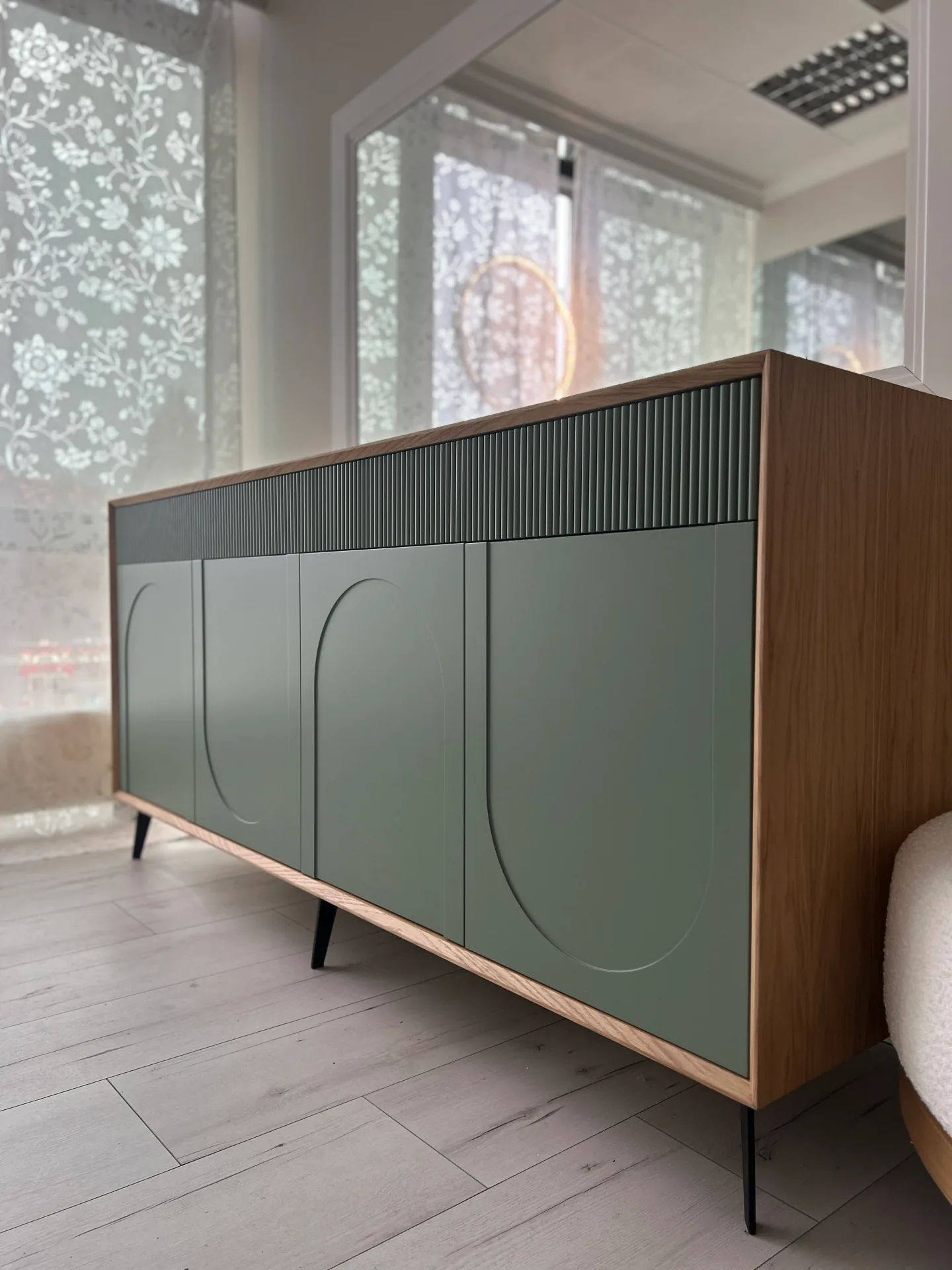 Niska szafka sideboard na wymiar w ujęciu narożnym, z szałwiowymi frontami zdobionymi łukami, poziomym pasem lameli i dębową ramą, na smukłych czarnych nóżkach.