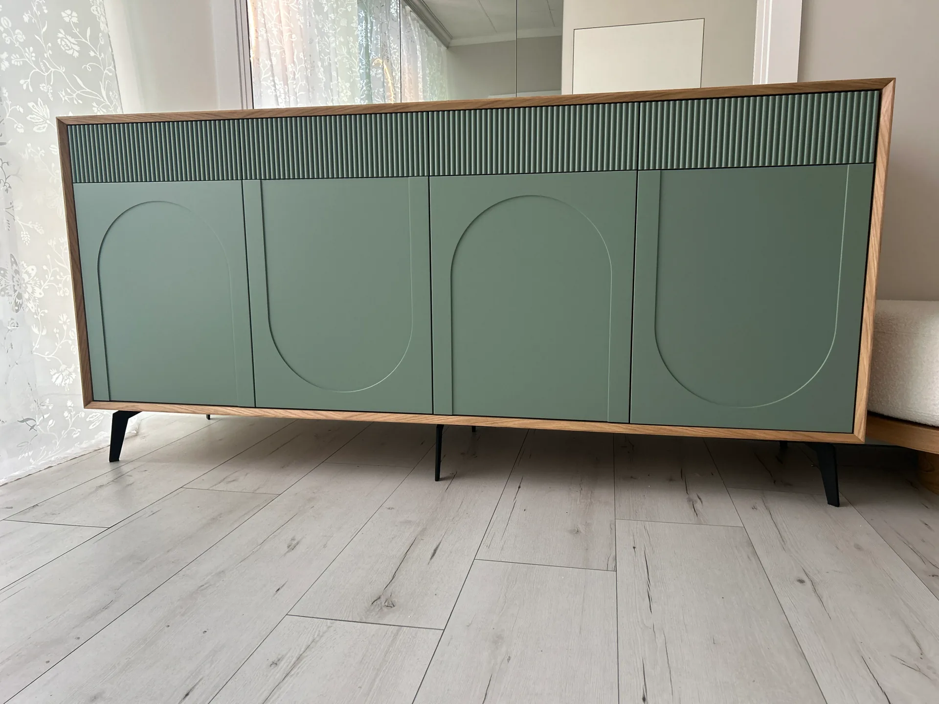 Niska szafka sideboard na wymiar w pełnym ujęciu frontowym, z czterema szałwiowymi frontami z łukami, poziomym pasem lameli i dębową ramą, na czarnych metalowych nóżkach.